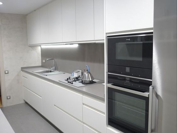 изящная белая кухня со столешницей и стеновой панелью из искусственного камня