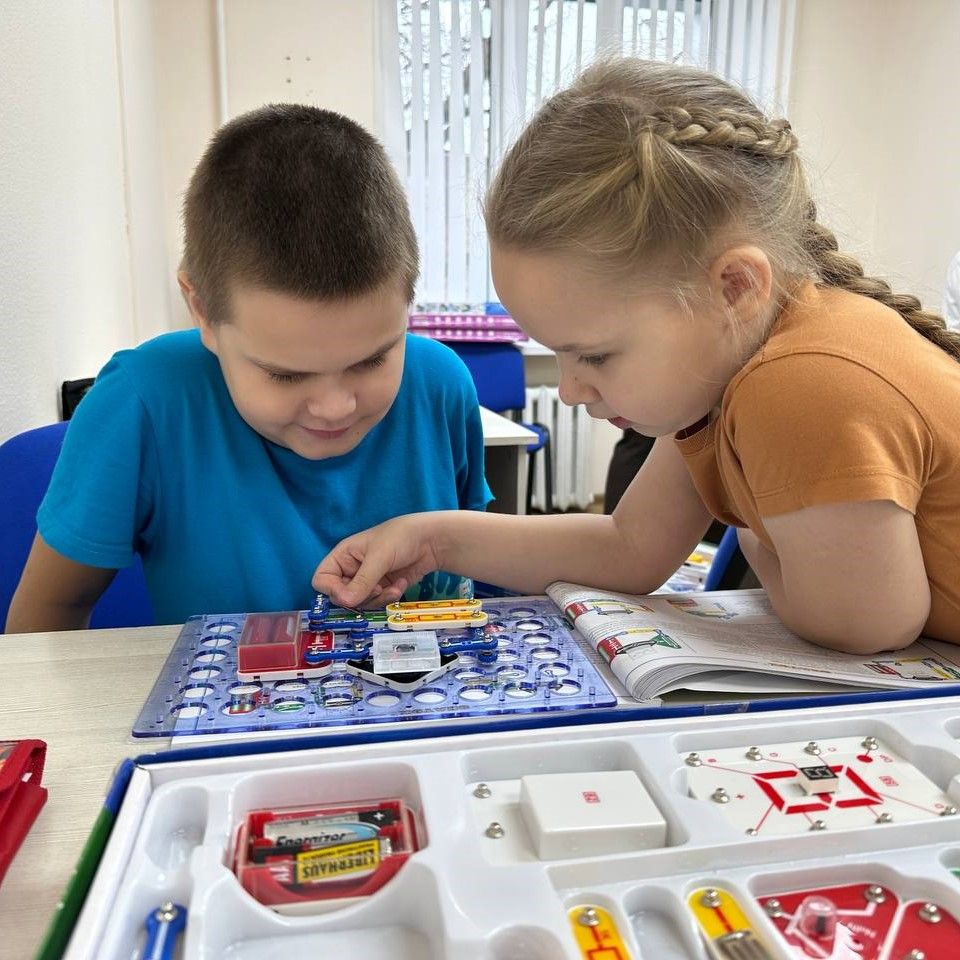 Ученики изучают инструкцию и схему из руководства набора Знаток