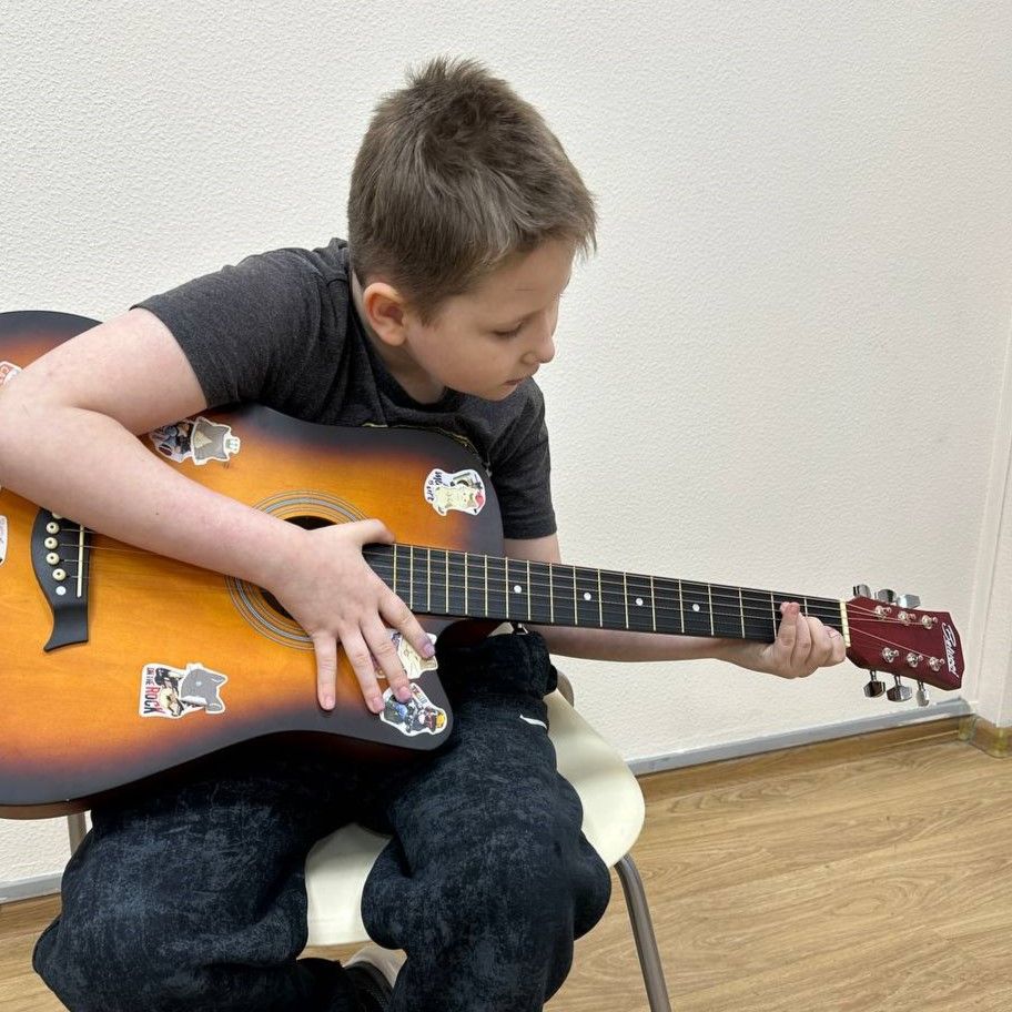 Мальчик играет боем на акустической гитаре