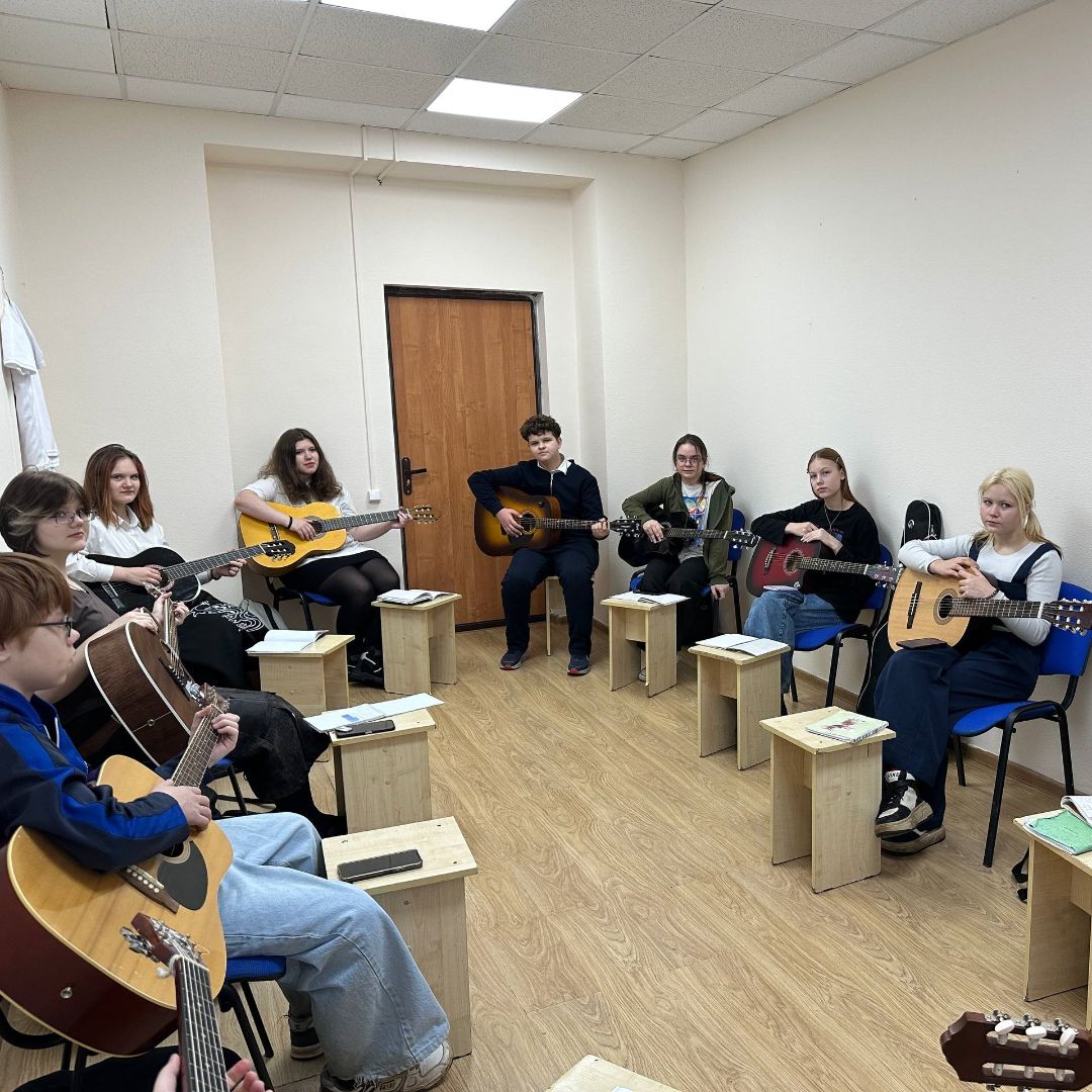 Дети и взрослые учатся играть на гитаре на совместном мастер-классе