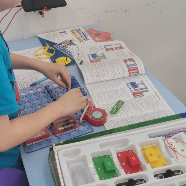 Школьник проверяет силу тока мультиметром в электронной схеме Знаток