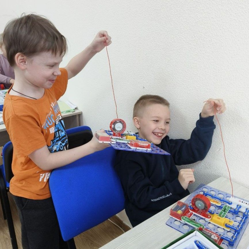 Двое учеников вместе собирают электрическую цепь на наборе Знаток