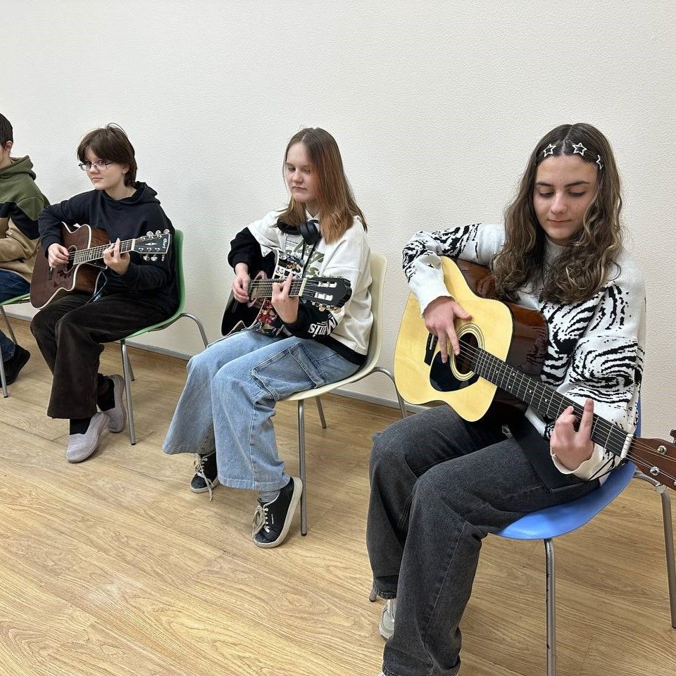 Ученики учатся играть на гитаре у опытного наставника