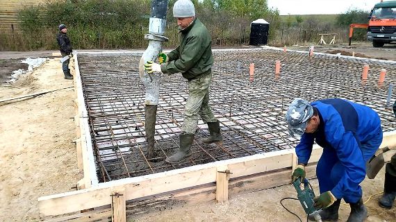 Строительная бригада заливает фундамент дома