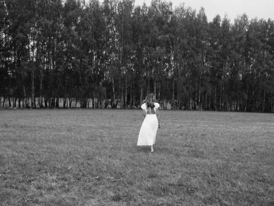 художник Анастасия Попова идет по полю днем летом