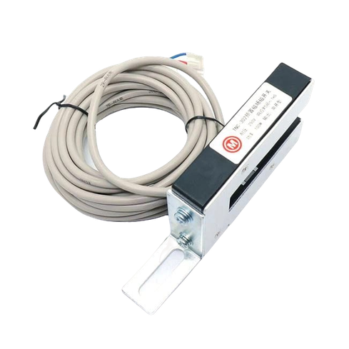 На этом изображении показан магнитный датчик, если судить по его компактному и функциональному дизайну. Датчик имеет металлическую деталь серебристого цвета, в которой с одной стороны имеется прорезь, а с другой - этикетка с технической информацией. Вокруг датчика намотан кабель кремового цвета, который может использоваться для подключения этого датчика к другим устройствам. Он обычно используется в системах безопасности, особенно в системах дверной или оконной сигнализации.