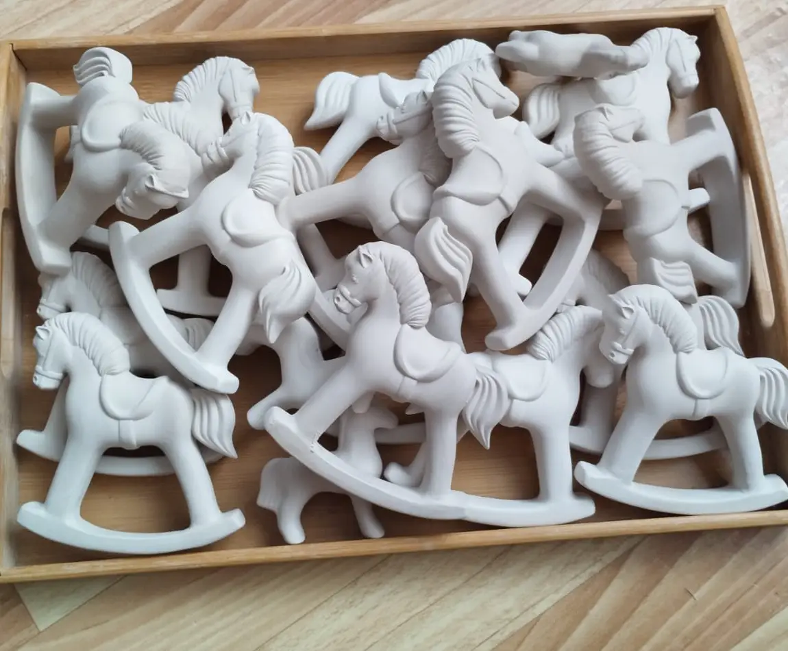 Множество фарфоровых лошадок в деревянном ящике после отливки