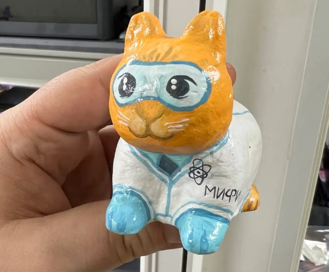 Кот-учёный из полимерной глины, расписанный вручную, крупный план в руке.