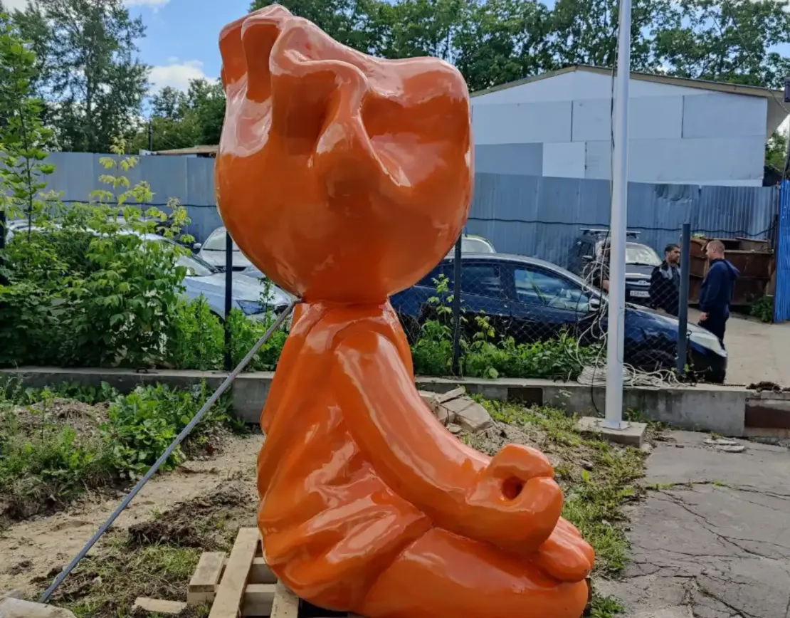 Вид на скульптуру пельменя сзади, в окружении зелени