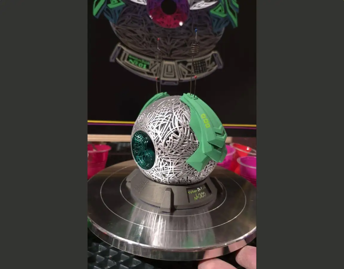 Фигура глаза с антеннами и зелёными элементами, покрашенная и установленная на подставку с подписью Cyber No.1
