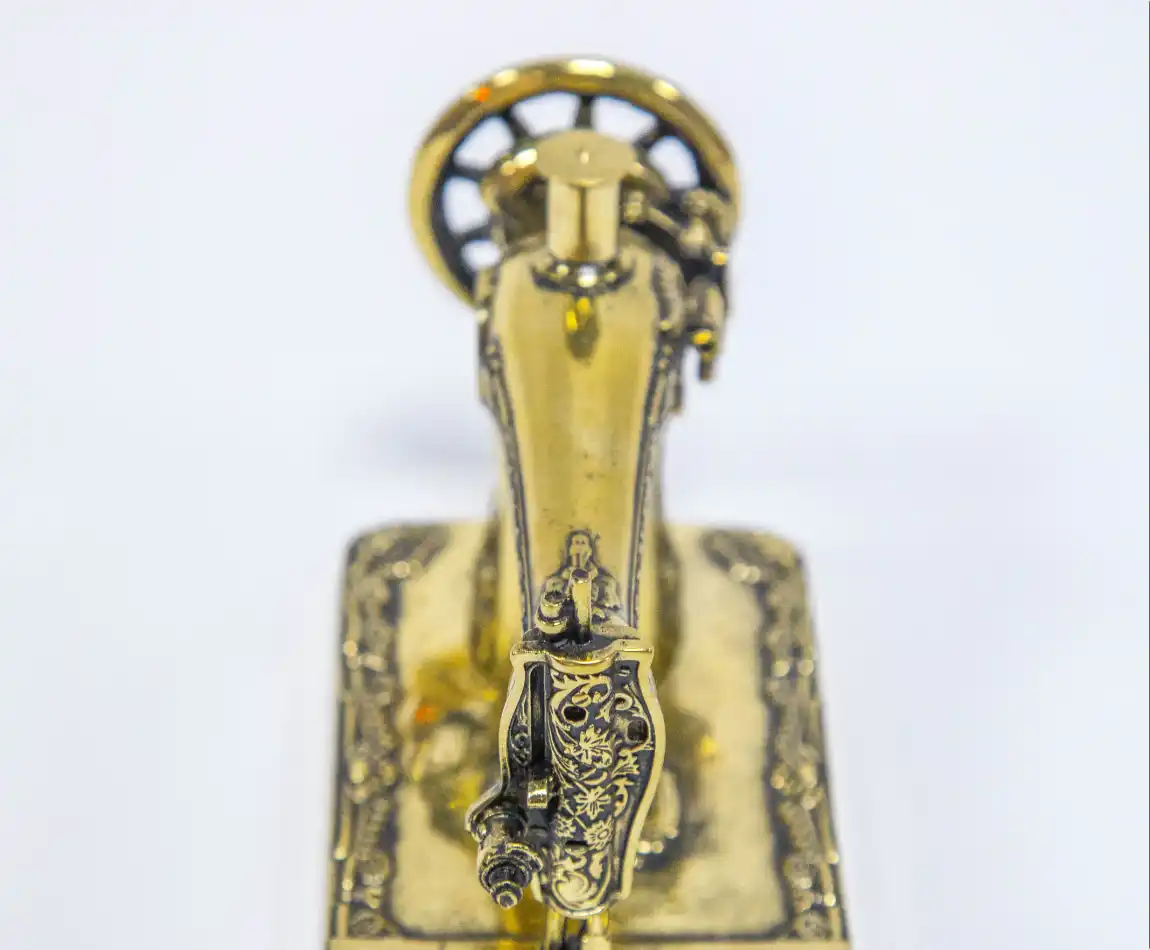 Миниатюрная машинка Singer из латуни — вид сверху на корпус и декоративные элементы.