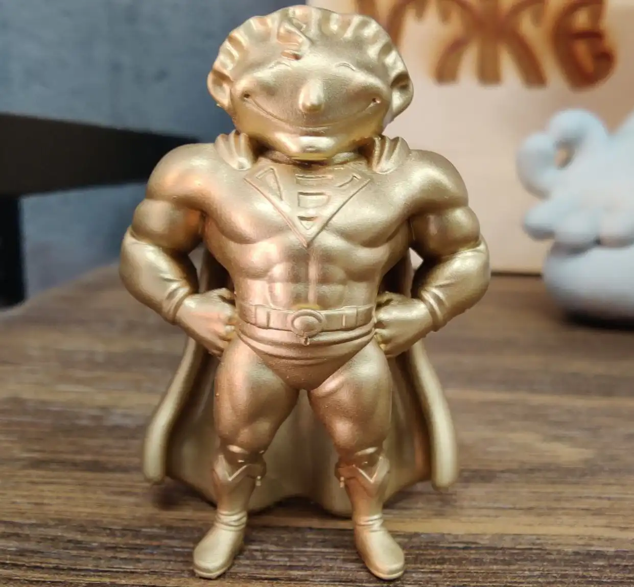 Фигурка пельмень-супермен с буквой «В» на груди, снятая крупным планом на макрообъектив, стоит на полке.