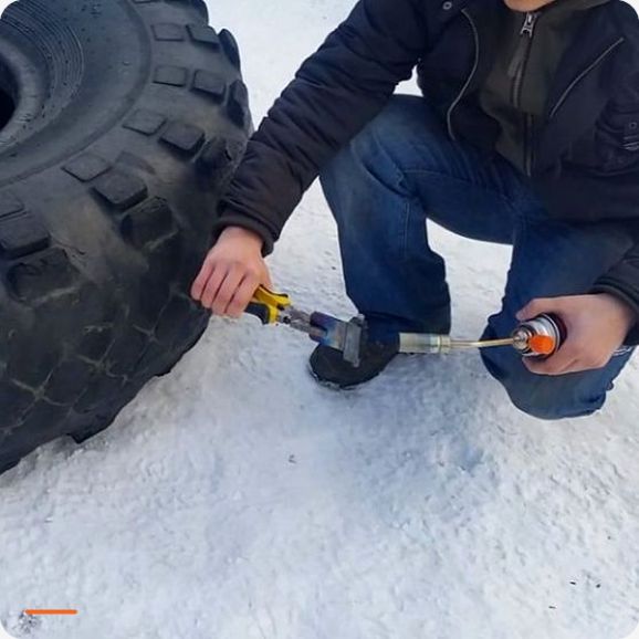 Клеймение шины в полевых условиях: держатель ТМШ-309 с пуансонами нагревают газовой горелкой на снегу у грузового колеса