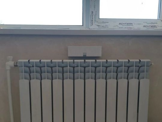 Приточный клапан Norvind в интерьере квартиры между подоконником и батареей