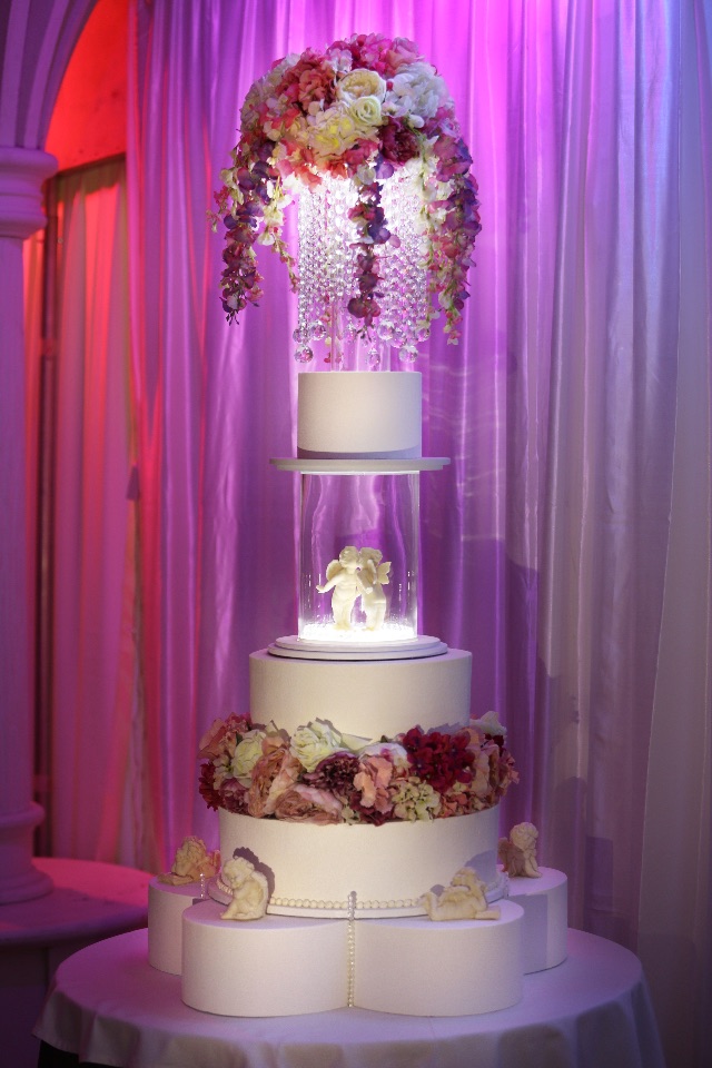 Многоярусный торт с цветами и кристаллами с вращающимися шоколадными ангелами в центре на заказ в Воронеже