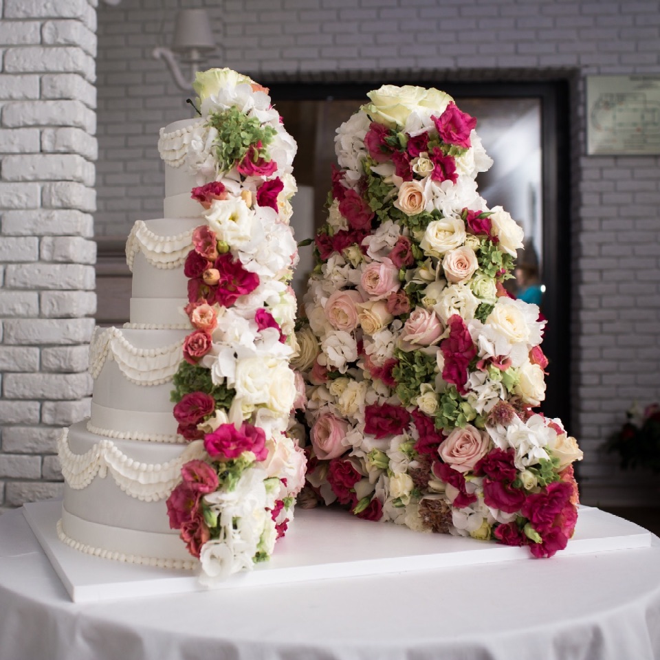 Оригинальный четырёхъярусный свадебный торт из двух половин с большим количеством живых цветов на заказ в Воронеже